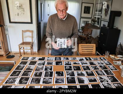 PRODUKTION - 03. Mai 2023, Nordrhein-Westfalen, Königswinter: Porträtfotograf Konrad Rufus Müller steht in seinem Wohnzimmer vor einer Reihe von Porträts der deutschen Kanzler. Konrad R. Müller hat alle deutschen Kanzler seit Adenauer fotografiert. Foto: Oliver Berg/dpa Stockfoto