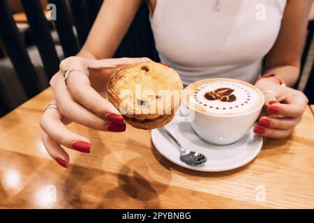 Ein Mädchen isst Muffin-Cupcake und trinkt Kaffee im Café Stockfoto