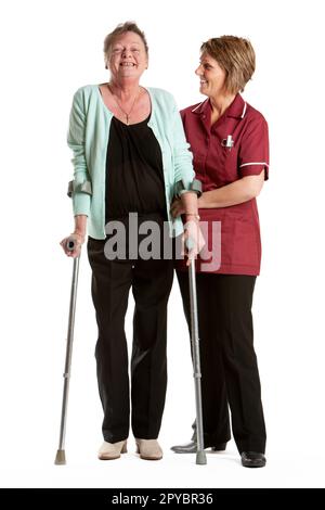 Fachkräfte Im Gesundheitswesen: Rehabilitation. Eine aufgeregte Seniorin, die von einer ermutigenden Krankenschwester wieder auf die Beine kommt. Aus einer Reihe von zugehörigen Bildern. Stockfoto