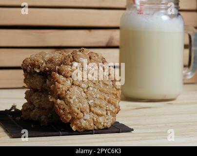Haferflocken-Erdnuss-Butterkekse mit Mandelmilch in rustikaler Küche Stockfoto