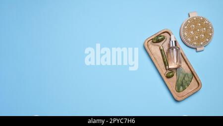 Glasflaschen mit Pipette, Massagegerät mit Steingesicht auf Holzständer, Draufsicht Stockfoto