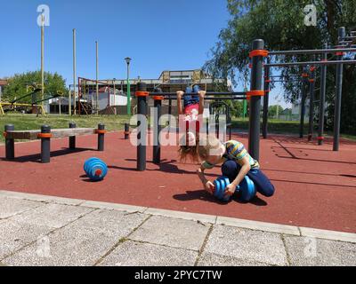 Sremska Mitrovica, Serbien. 6. Juni 2020. Flip-Flops, Gewichtheben und Kraftübungen. Zwei Teenager gehen in Simulatoren Sport treiben, Kinder auf einem Sportplatz Stockfoto