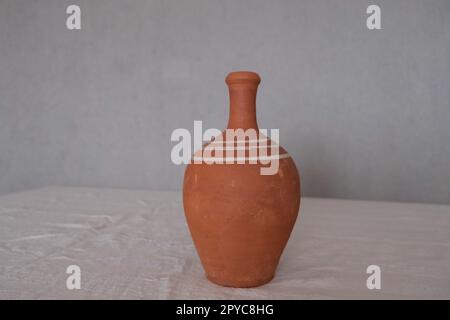 Vorderansicht eines alten unlackierten antiken Keramikkastens auf einer weißen Tischdecke. Tonkrug zum Trinken von Wein oder Wasser. Stockfoto