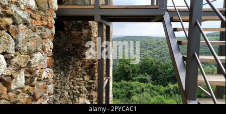 Ruinen einer alten Festung in Vrdnik, Sremska Mitrovica, Vojvodina, Serbien. Alte Steinmauern, Bergentfernungen. Metalltreppe zum Himmel. Historische Sehenswürdigkeiten. Stockfoto