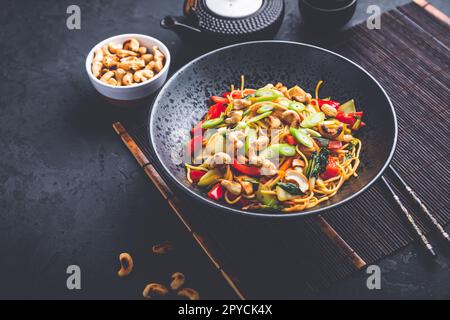 Gebratene Nudeln mit Hühnchen, Gemüse und gerösteten Cashewnüssen umrühren Stockfoto