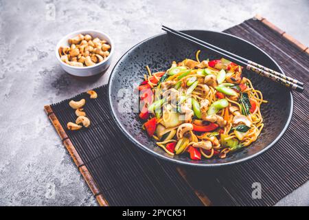 Gebratene Nudeln mit Hühnchen, Gemüse und gerösteten Cashewnüssen umrühren Stockfoto