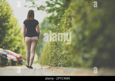 Blinde Frau, die mit ihrem weißen Stock auf den Straßen der Stadt unterwegs ist Stockfoto