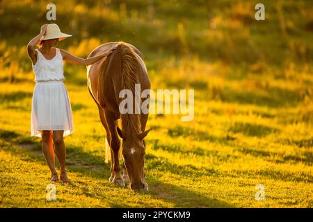 Junge Frau mit ihrem braunen Pferd draußen Stockfoto