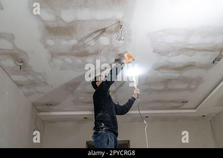 Handschleifen der Gipskartondecke mit einer Kelle Stockfoto