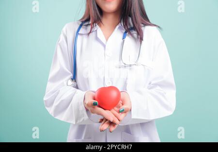 Doktor, wunderschöne junge Frau, die steht, lächelt, einen roten Kopf in der Hand hält Stockfoto