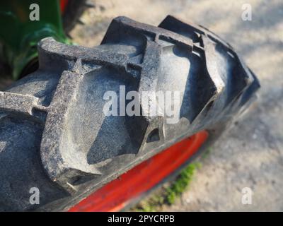 Reifen von einem Motorgrubber. Nahaufnahme eines Rades von einem kleinen Landwirtschaftstraktor. Gummigewinde. Industriedetails. Stockfoto