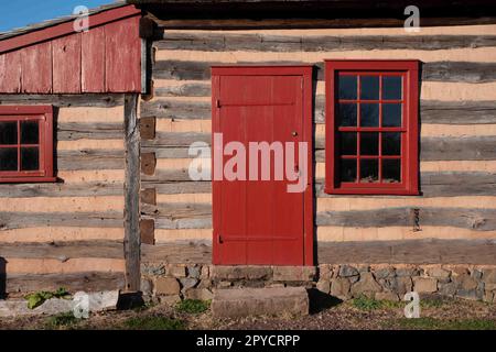 Koloniale Blockhütte außen mit rotem Fenster und Tür Stockfoto