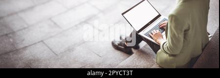 Junge Frau mit Laptop, die auf der Treppe sitzt. Stockfoto