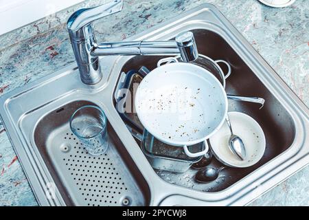 Geschirrspülmaschine - ein Haufen schmutzigem Geschirr im Spülbecken Stockfoto