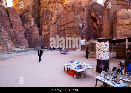 27. Januar 2023 Petra, Jordanien. Die Einheimischen verkaufen Souvenirs, orientalische Schals, Schmuck und Magnete. Alte Schnitzermauern im Hintergrund. Stockfoto