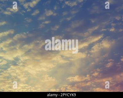 Wunderschöner, rosafarbener und gelber Sonnenuntergang am Himmel. Die Wolken werden von den tiefen Sonnenstrahlen gefärbt. Blauer Himmel. Wundervolle Landschaft. Stockfoto