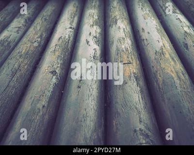 Ein Bauholz für den Einsatz im Bauwesen ohne Längssägen. Rundes Holzsortiment. Bruchstücke der Konstruktion von abgerundeten Holzstämmen. Der Einfluss von Feuchtigkeit auf Holz. Stockfoto