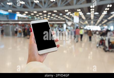 Weibliche Hand mit Smartphone und verschwommenem Hintergrund des Flughafenterminals. Stockfoto