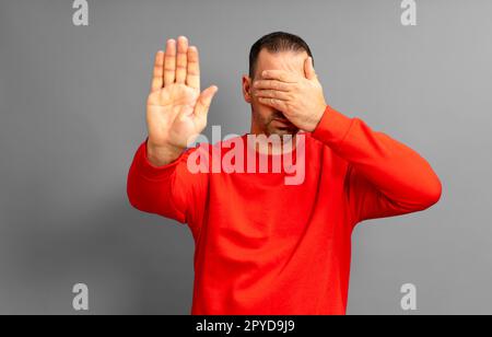 Ich will mir das nicht ansehen. Ignoriere das Porträt eines bärtigen lateinamerikanischen Mannes in seinem 40s. Stand, er schloss seine Augen und zeigte eine Stoppzeichen-Geste Stockfoto
