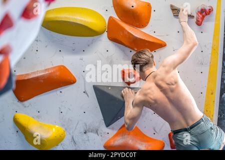 Junger Mann auf einem Felsbrocken, kletterend Stockfoto