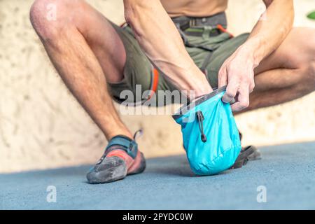 Auftragen von Magnesium auf die Hände aus dem Beutel vor dem Klettern auf die Kletterwand Stockfoto