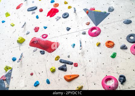 Künstliche Kletterwand mit Griffen und Karabinern im Innenraum Stockfoto