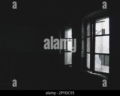 Beängstigende Fenster. In einem verlassenen Haus. Blick auf kaputte Fenster ohne Vorhang. Grunge-Szene. Das Licht scheint durch alte Holzrahmen mit Glasscherben. Das Konzept von Verlassenheit und Nützlichkeit Stockfoto