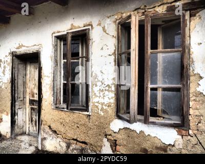 Altes Haus mit Fenstern und einer Tür. Einstürzendes Landhaus. Der Begriff Urbanisierung und Vergessenheit des Mutterlandes. Verlassenes Haus. Zerbrochenes Glas in den Fenstern und herunterfallender Putz. Serbien. Balkan Stockfoto