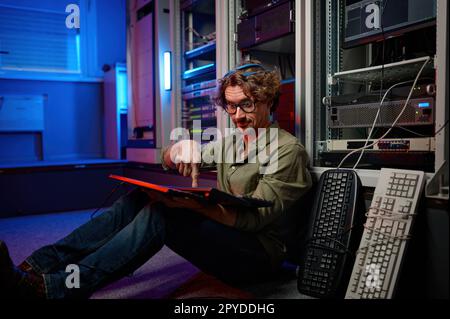 Überarbeiteter Rechenzentrumsingenieur, der die Tastatur im Serverraum eines Supercomputers verwendet Stockfoto