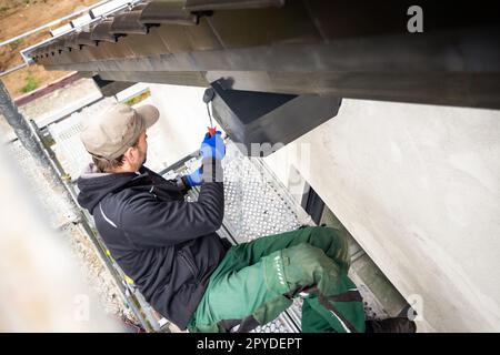 Handwerker, der Holzbeize auf einen Dachbalken eines Hauses aufbringt Stockfoto