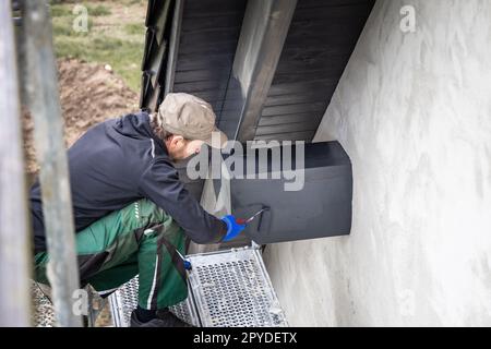 Handwerker, die Holzflecken auf einen Dachbalken eines Hauses auftragen Stockfoto