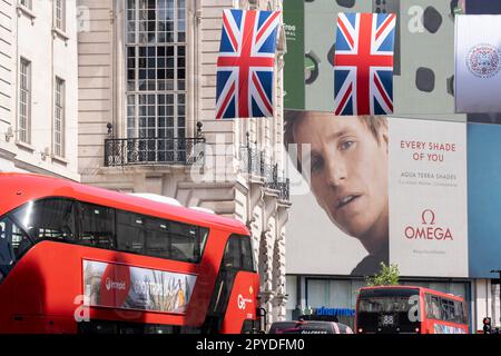 Nur vier Tage vor der Krönung von König Karl III., nach dem Tod seiner Mutter, Königin Elizabeth II. Im letzten Jahr, hängen die Flaggen von Union Jack neben Omega Uhren Werbung, die vom Schauspieler Eddie Redmayne, am Piccadilly Circus, am 3. Mai 2023, in London, England, unterstützt wird. Stockfoto