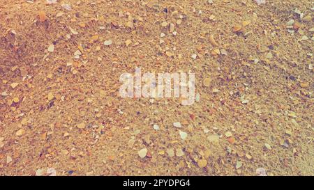 Sand mit Muschelhintergrund. Nasser grober Quarzsand. Kaputte Muscheln. Strand nach starkem Regen. Kieselgel. Quarzsand, natürlich braunes Material nach Sturm. Dellen von Tropfen im Sand. Anapa Stockfoto