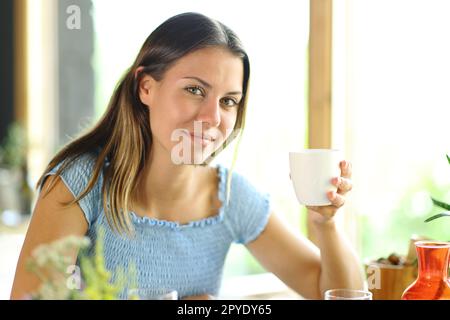 Frau mit Kaffeetasse in einem Restaurant posiert Stockfoto