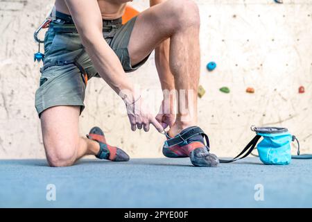 Kletterschuhe neben der Kletterwand anziehen Stockfoto