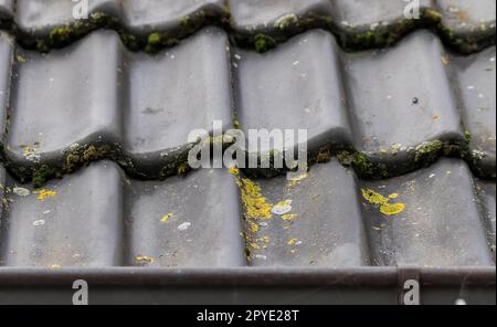 Nahaufnahme vieler schwarzer Dachziegel auf dem Dach eines Wohngebäudes. Stockfoto