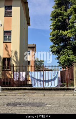 Wäscheleine in einem Hof einer Eigentumswohnung, die im Frühling von einem Zaun am Straßenrand in einem Dorf in der italienischen Landschaft gesehen wurde Stockfoto