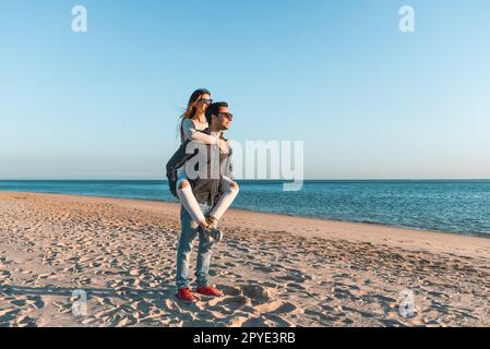 Ein glückliches Paar steht am Sandstrand und genießt die wunderschöne Meereslandschaft. Stockfoto