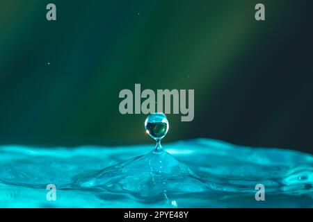 Wassertropfen fallen dicht in das blaue Wasser, was es zum perfekten Zentrum in der Natur macht Stockfoto