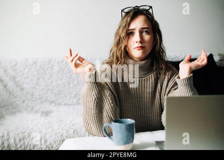 Gestresste Buchhalterin, die von zu Hause aus arbeitet, mit Problemen mit Laptops oder Finanzberichten konfrontiert ist, besorgt vor der Kamera Stockfoto