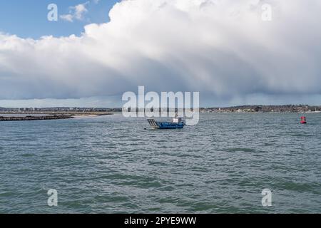 Kleines Boot im Hafen von Poole mit schweren Wolken und Regen über Poole im Hintergrund, Dorset, England Stockfoto