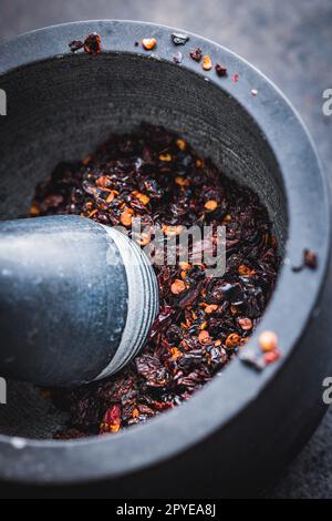 Geräucherte, trockene Chili-Pfefferflocken. Zerkleinerte rote Paprika in Mörtel. Stockfoto