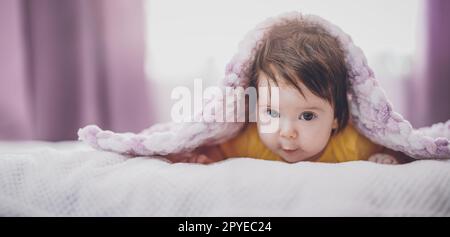 Niedliches kleines Baby, das unter einer rosa Decke liegt. Stockfoto