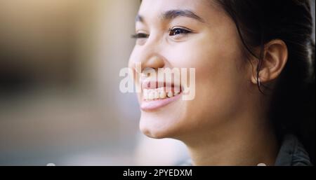 Sie verbreitet ihr Glück heute in der ganzen Stadt. Nahaufnahme einer attraktiven jungen Frau, die in der Stadt lächelt. Stockfoto