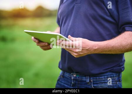 Moderne Technik für den modernen Bauern. Ein unerkannter Mann, der ein Tablet auf einem Bauernhof benutzt. Stockfoto