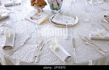 Brautmise en Place mit weißer Tischdecke aus Spitze und silbernem Besteck. Stockfoto