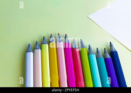 Viele bunte Filzstifte zum Zeichnen in einem Notizbuch und Album auf gelbem Hintergrund. Stockfoto