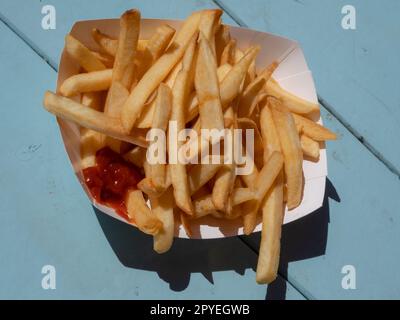 Eine Portion Pommes zum Mitnehmen auf Einem Campingtisch am Strand Stockfoto