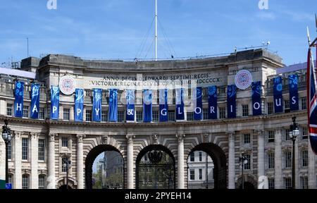 Das offizielle Logo der Krönung von König Karl dem Dritten als Teil der „Happy & Glorious“-Banner, die von Admiralty Arch, London, hängen Stockfoto