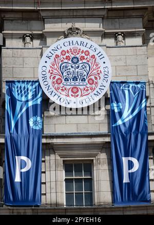 Das offizielle Logo der Krönung von König Karl dem Dritten als Teil der „Happy & Glorious“-Banner, die von Admiralty Arch, London, hängen Stockfoto